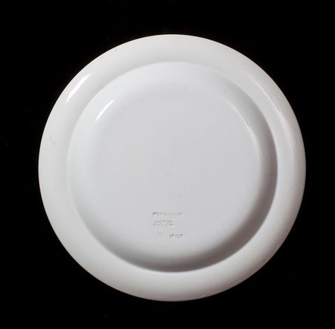 Plate. The underside of a white plate is stamped \“Wedgwood Made in England\”.